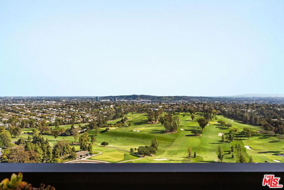 Panoramic view of a vast landscape with a golf course and distant city skyline.