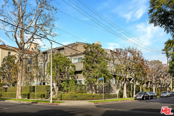 Front view of a multi-story residential building with surrounding trees.