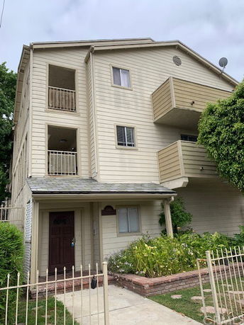 Front view of a multi-story residential building with balconies and a small entrance porch.
