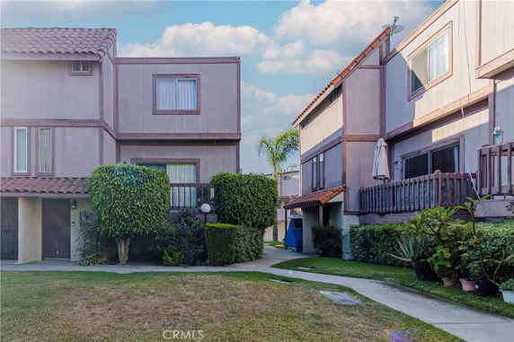 Front view of two-story residential buildings with tiled roofs and small yards.