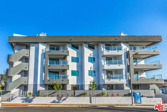 Front view of a modern multi-story apartment building with balconies.