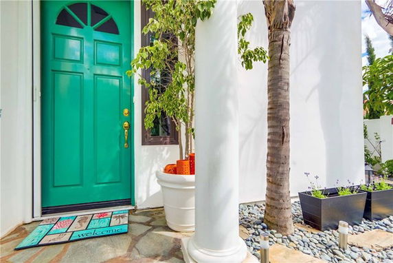 Front view of a house entrance with a green door and white column.