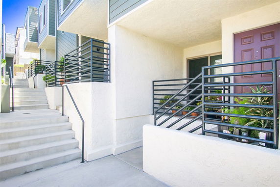 Front view of a multi-story residential building with stairs and a patio.