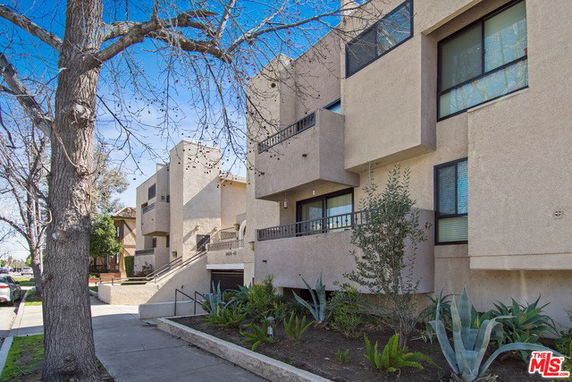 Front view of a multi-story residential building with balconies and large windows.