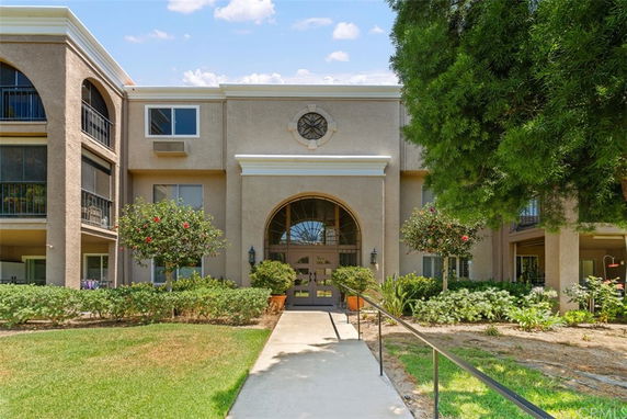 Front view of a multi-story building with an arched entrance and a clock above the door.