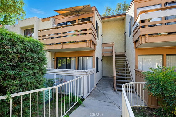 Front view of a multi-story building with balconies and an external staircase.