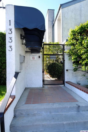 Entrance view of a building with a blue awning and gate.