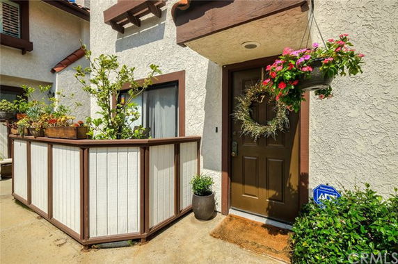 Front view of a house entrance with a small fenced patio and a decorated door.