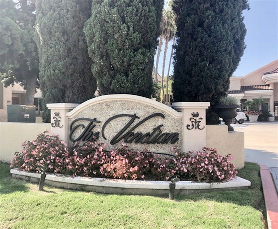 Front view of a building entrance with a sign and landscaping.