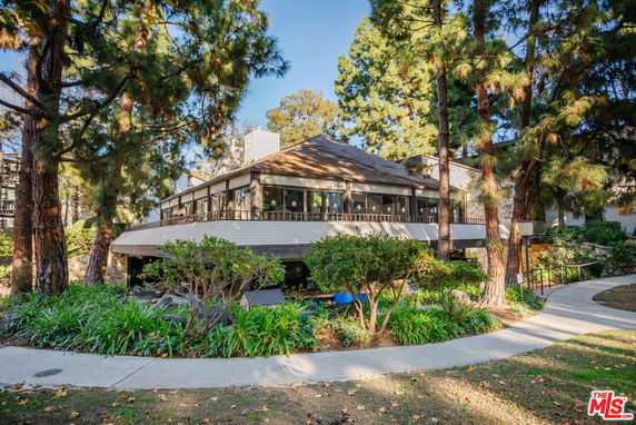 Front view of a building with large windows surrounded by trees and greenery.