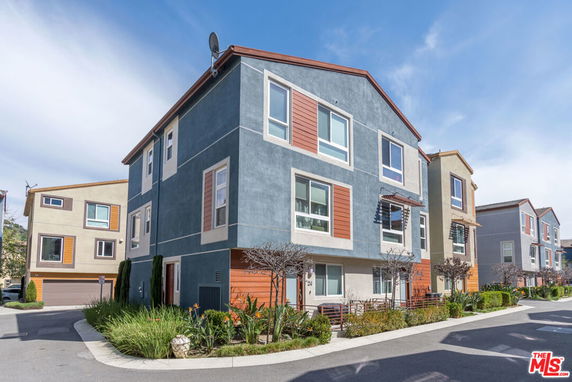 Front view of a modern three-story residential building with large windows.