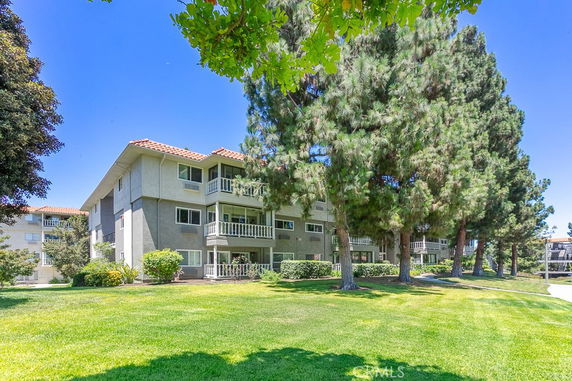 Front view of a multi-story apartment building with balconies and lawn.