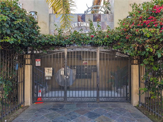 Front view of a gated entrance to a building with decorative metalwork and foliage.