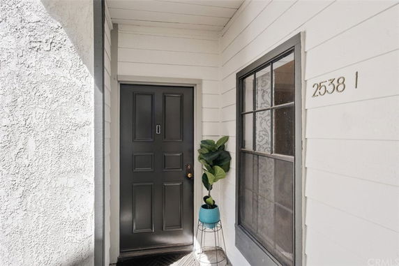 Front entrance view of a house with a black door and white siding.