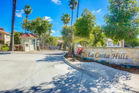 Front view of a gated community entrance with a sign reading 'La Costa Hills'.