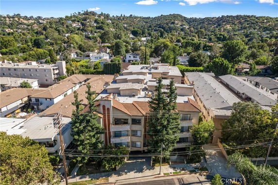 Aerial view of a multi-story apartment building with a tiled roof and trees in front.