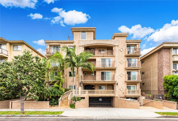 Front view of a multi-story apartment building with balconies and decorative railings.