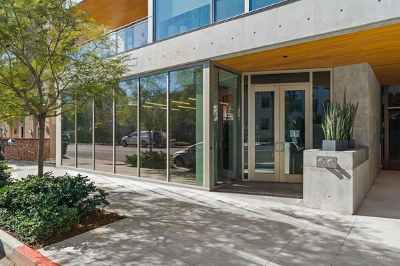 Front view of a modern building with large glass windows and a concrete entrance.