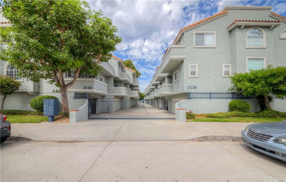 Front view of an apartment complex with multiple stories and a gated entrance.