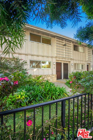 Front view of a two-story house with a garden and a fence.