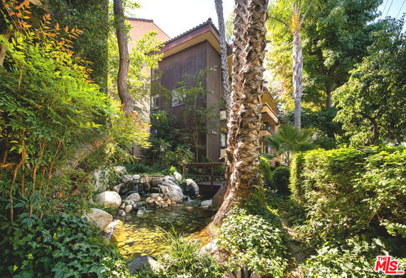 Front view of a house surrounded by lush greenery and trees.