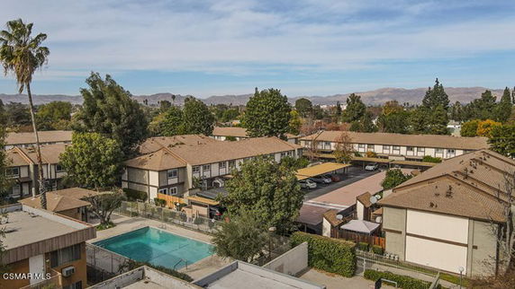 Panoramic view of residential complex with multiple buildings and a swimming pool.