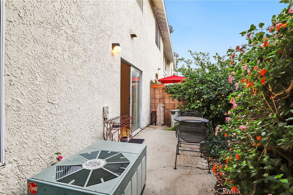 Outdoor patio area with chairs and a table, next to a building wall.