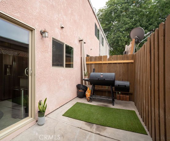 Outdoor area with grill and small artificial grass patch next to a building.