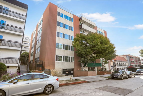 Front view of a multi-story apartment building with large windows and balconies.
