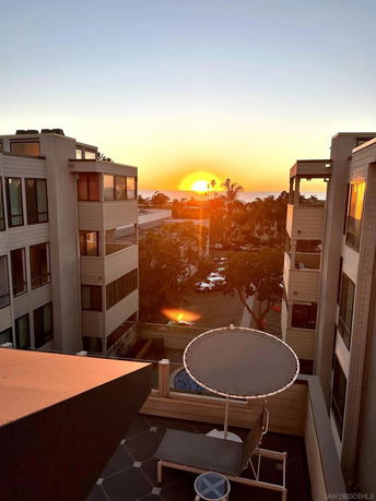Panoramic view of buildings with sun setting over the ocean in the background.