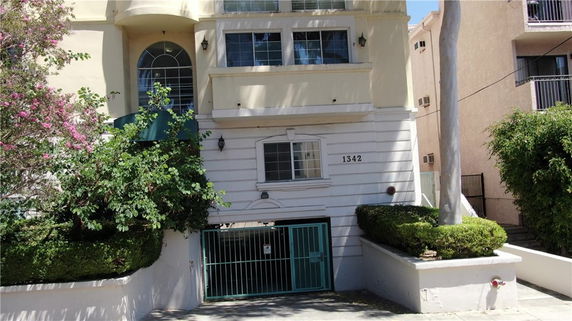 Front view of a multi-story building with a gated entrance and arched window.
