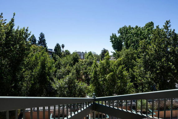 Panoramic view of trees and distant buildings seen from a balcony.