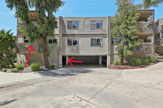 Front view of a multi-story residential building with balconies and covered parking.