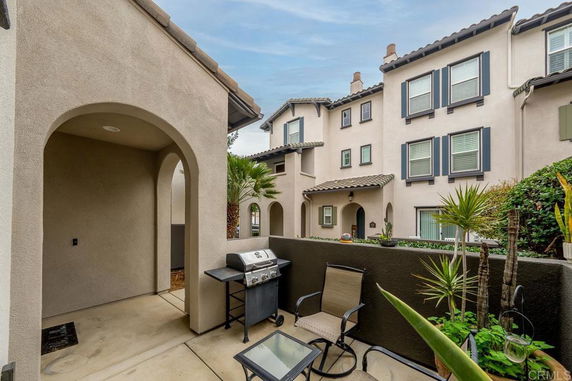 View of multi-story residential building with archways and outdoor sitting area.