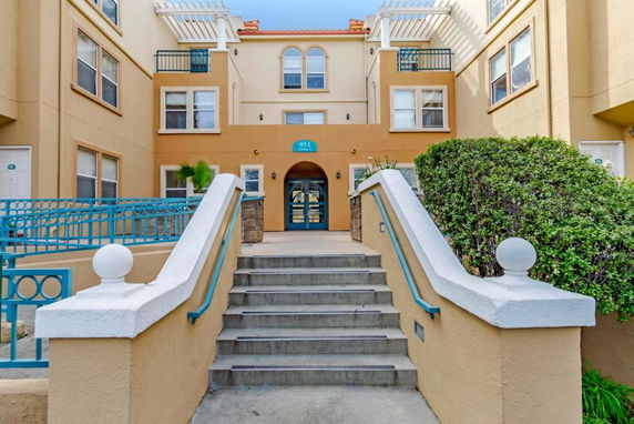 Front view of a multi-story building entrance with stairs and teal railings.