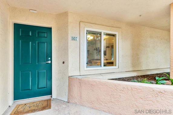 Front entrance of a house with a green door and a window beside it.