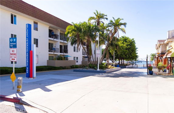 Front view of a multi-story building with balconies and palm trees nearby.