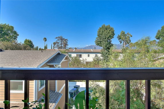 View from a house showing neighboring rooftops and trees with a blue sky.