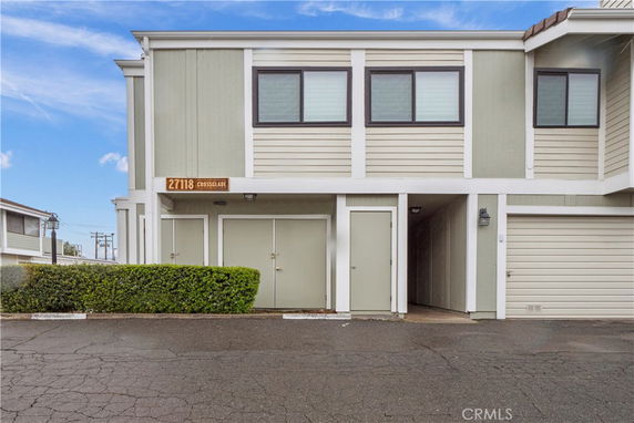 Front view of a two-story house with green and beige siding and a sign above the door reading 27118 Crossglade.