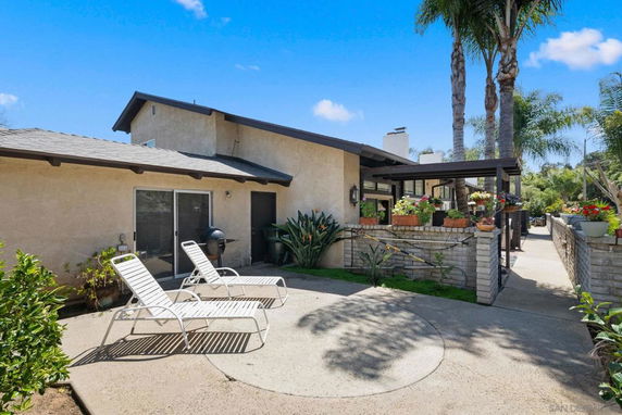 Front view of a single-story house with a patio and lounge chairs.