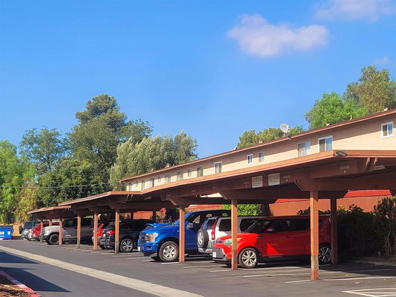 Covered outdoor parking area with multiple vehicles parked.