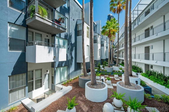View of a modern multi-level apartment building with balconies and landscaped garden area.