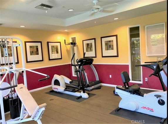 Interior view of a gym area with exercise equipment and framed artwork on the walls.