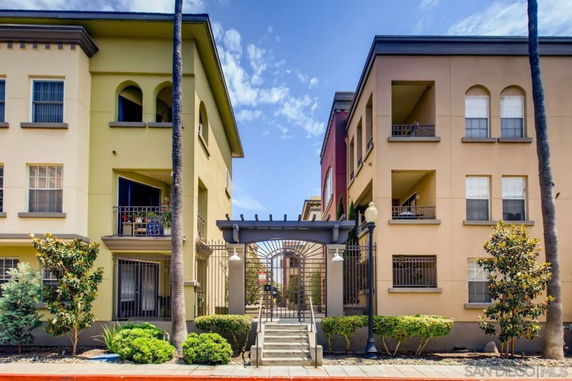 Front view of a multi-story apartment building with balconies and a gated entrance.
