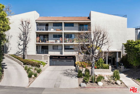 Front view of a multi-story residential building with balconies and garage entrance.