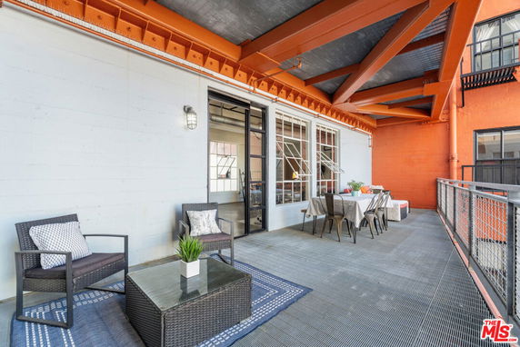 Rooftop area with seating and dining furniture under a metal framework.