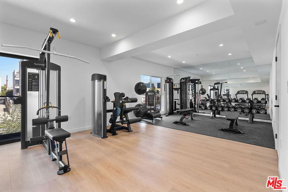 Room with gym equipment including weights and machines.