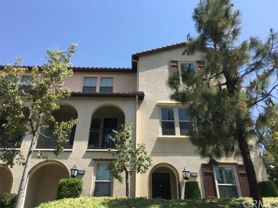 Front view of a multi-story residential building with arched balconies and multiple windows.