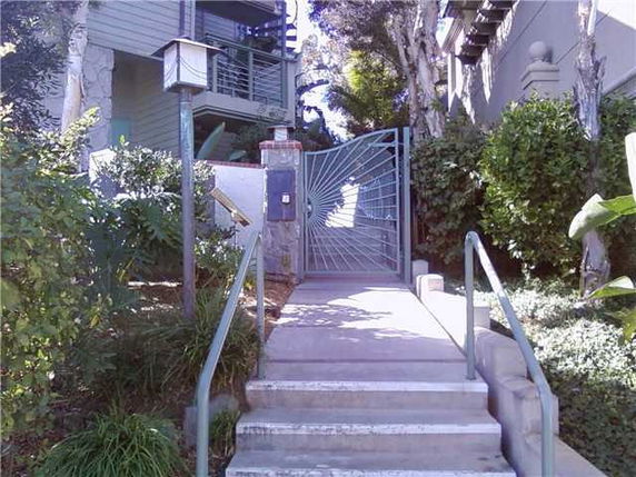 Front view of a residential building with gated entrance and stairs.
