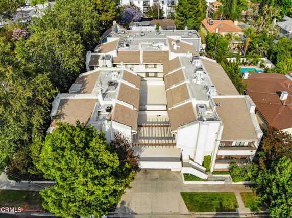 Aerial view of a large multi-story residential building with a complex layout and multiple rooftops.
